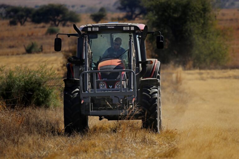 Operador dirigindo trator agrícola em campo, treinamento para curso gratuito